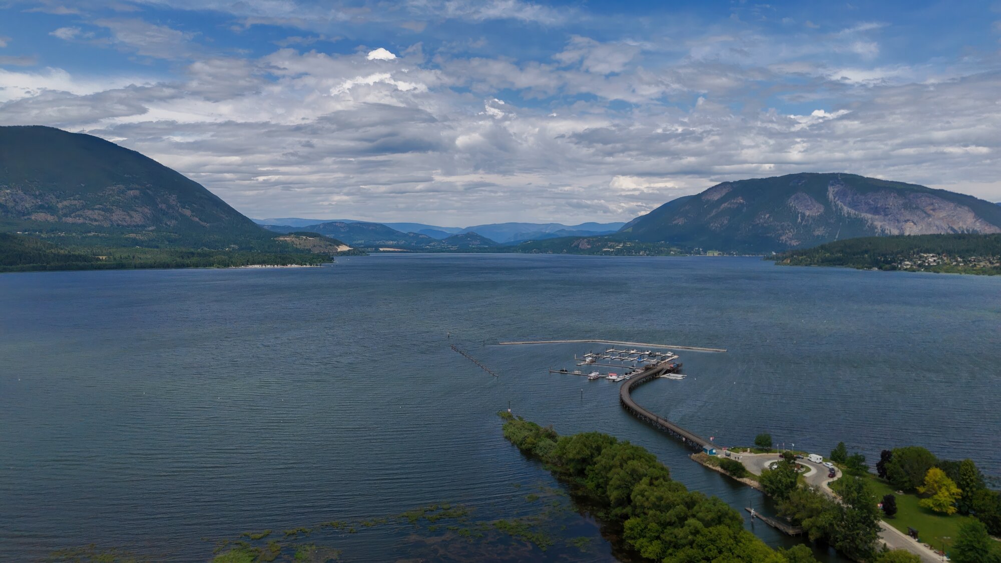An aerial view of Shuswap Lake and Salmon Arm's curved wharf on a summer day